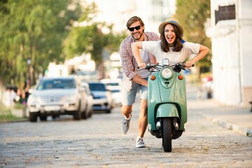 Fototapeta premium Laughing couple riding on a scooter in town