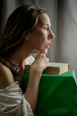 woman in a white blouse with a Carmen neckline with her hands resting on an old book in a romantic attitude VI