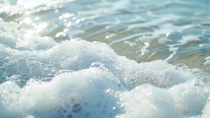 Fototapeta premium Close-up of glistening sea foam with sunlight reflecting off gentle waves in the background.