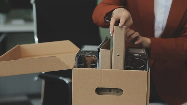 Upset female employee packing belongings in box, frustrated stressed girl getting fired from job ready to leave on last day at work. sad office worker desperate from work