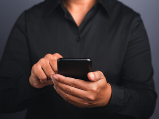 Smartphone in the hand of a businesswoman against a black background.