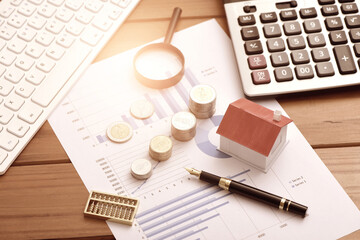 Small houses, coins, and office supplies placed on financial data reports