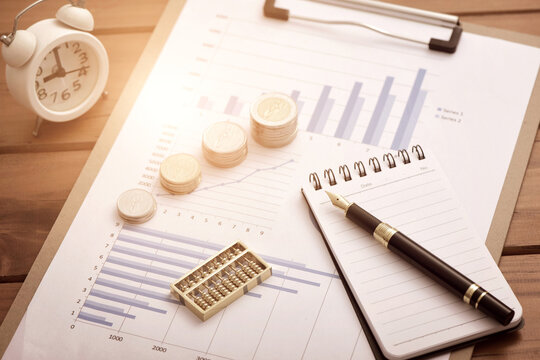 Coins, abacuses, and pens placed on financial data reports