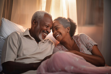 An elderly dark-skinned man and woman enjoying a moment of closeness as they lay together on a bed, expressing love and romance