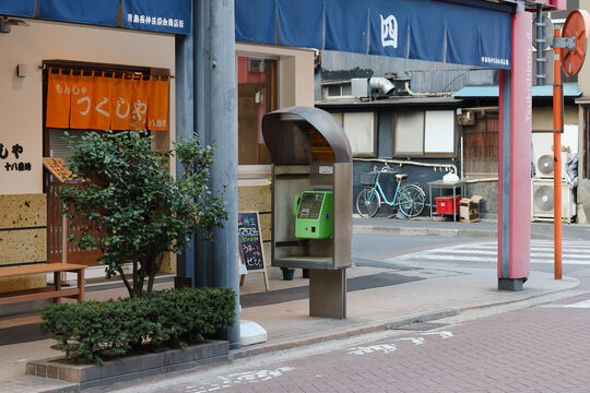TOKYO, JAPAN - November 9, 2022: View of Tsukishima Monja Street with restaurant and payphone.