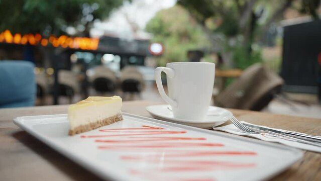 Lemon cheesecake and a mug of hot drink, steam from the hot. Cafe on the street.