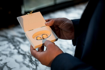 The groom holding the wedding rings in box