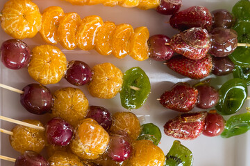 Candied colorful fruits on sticks on a street stall.Selective focus.