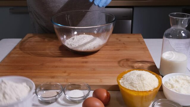 uomo versa le farine e il lievito nella ciotola poi mescola con le mani