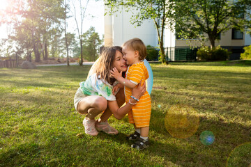 Cute children playing together outdoors on green summer lawn. Sibling hugging happily.