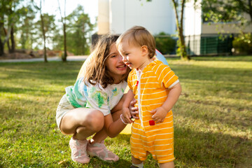 Cute children playing together outdoors on green summer lawn. Sibling hugging happily.