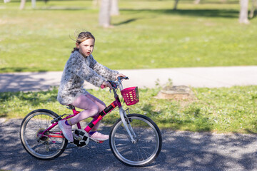 A young girl is riding a pink bicycle with a basket on the front
