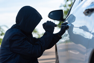 Close-up Man dressed in a black holding screwdriver to break the lock and steal a vehicle on the...