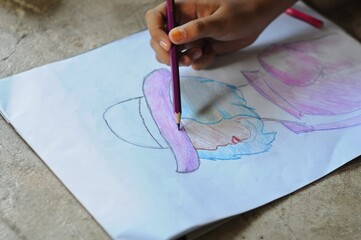 A child's hands are coloring his work