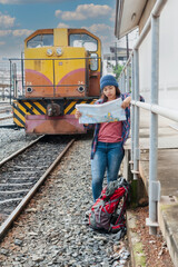 Fototapeta na wymiar Traveler and tourist asia young women wearing backpack holding map, waiting for a train. Travel Concept.