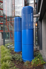 Fototapeta na wymiar Two Tall Blue Ventilation Outlet Towers at Modern Building in City