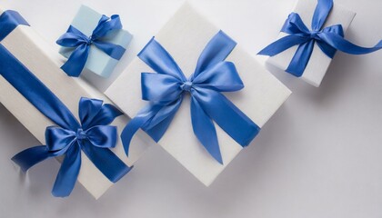 Top view of blue and white giftboxes with blue satin ribbon bow isolated on white background with empty space
