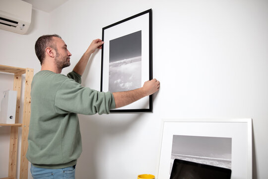 Man hanging pictures on the wall.