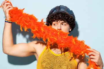 Close up young gay Latin man wear mesh tank top hat yellow clothes hold cover mouth with tinsel...