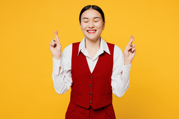 Young corporate lawyer employee business woman wear formal red vest shirt work at office wait special moment, keep fingers crossed, make wish isolated on plain yellow background studio Career concept
