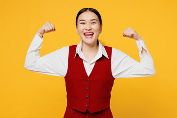 Side view young fun corporate lawyer employee business woman of Asian ethnicity wear formal red vest shirt work at office show muscles biceps isolated on plain yellow background studio Career concept