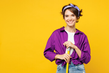 Young smiling happy fun cheerful woman wears purple shirt casual clothes do housework tidy up hold...