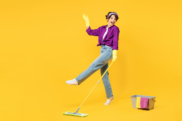 Full body side view young woman wear purple shirt casual clothes do housework tidy up hold in hand mop bucket with water wash floor isolated on plain yellow background studio. Housekeeping concept.