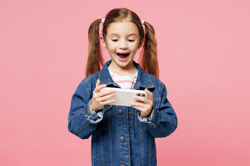 Little child kid girl 7-8 years old wears denim shirt use play racing app on mobile cell phone...