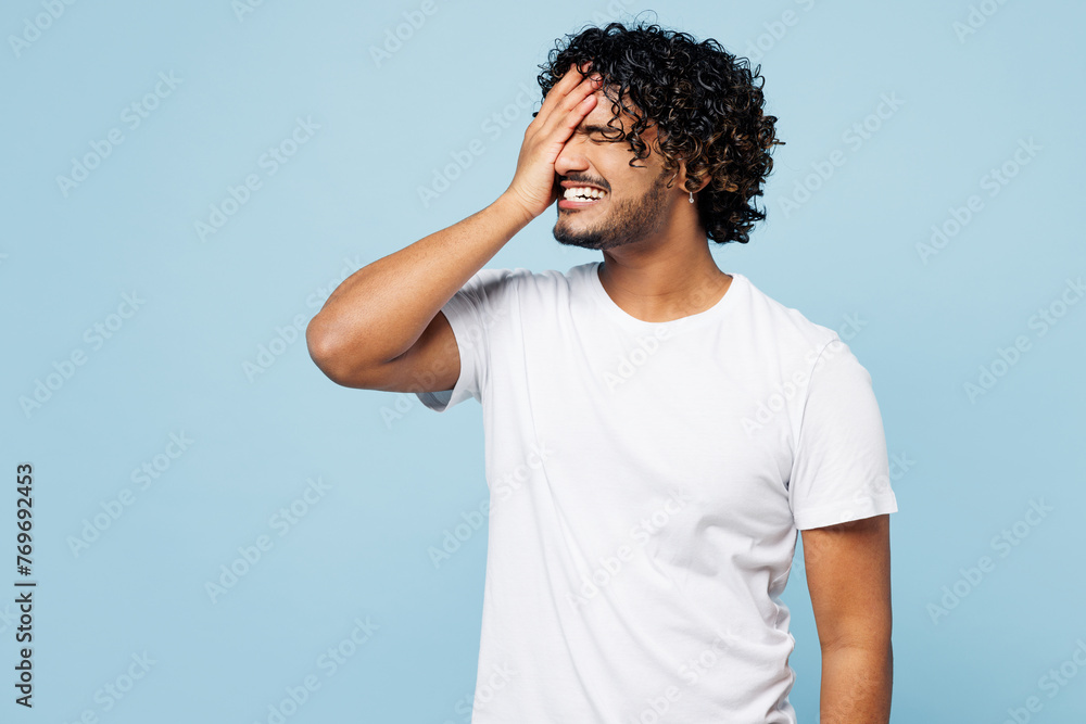 Wall mural Young sad Indian man wear white t-shirt casual clothes put hand on face facepalm epic fail mistaken omg gesture isolated on plain pastel light blue cyan background studio portrait. Lifestyle concept. - Wall murals