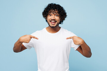 Young surprised shocked fun happy Indian man he wear white t-shirt casual clothes point index finger on himself isolated on plain pastel light blue cyan background studio portrait. Lifestyle concept.