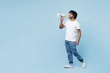 Full body young happy Indian man he wear white t-shirt casual clothes hold in hand megaphone scream announces discounts sale Hurry up isolated on plain pastel blue cyan background. Lifestyle concept.