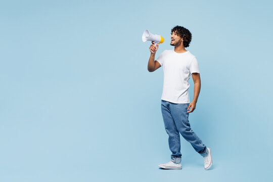 Fototapeta Full body young happy Indian man he wear white t-shirt casual clothes hold in hand megaphone scream announces discounts sale Hurry up isolated on plain pastel blue cyan background. Lifestyle concept.