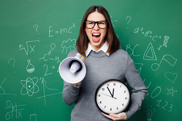 Young mad smart teacher woman wear grey casual shirt glasses hold clock scream shout in megaphone...