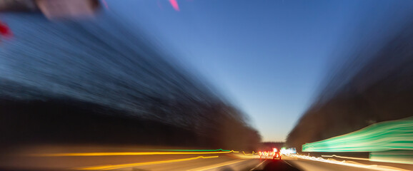 A blurry shot of a highway at night with a car in the foreground