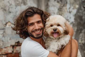 A handsome man with lustrous curly hair grins as he affectionately holds his fluffy, cheerful dog against an urban backdrop.