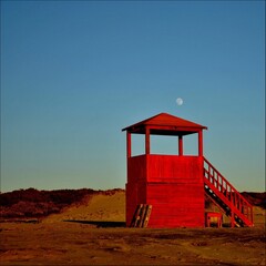 Red security guard booth located in Lido di Ostia, Lazio, Italy with the Moon in the background