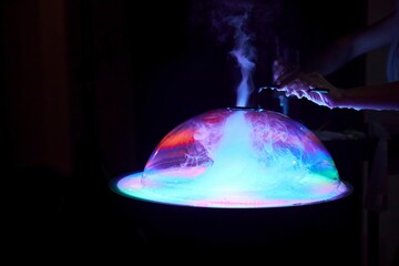 Fototapeta na wymiar A show of illuminated soap bubbles. A woman's hand