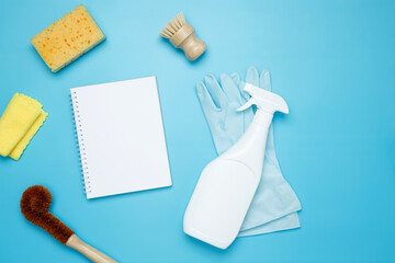 Various accessories cleaning products, sprays, rags, sponges and brushes. Mock up white notebook. Top view, flat lay, copy space