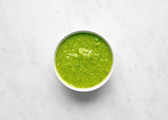 Bowl of basil pesto top view on white marble background top view, green vegetable sauce - 769703889
