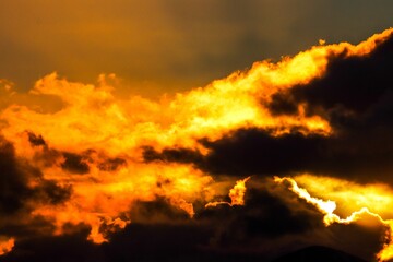 Dramatic orange and yellow sunset sky behind a range of majestic mountain peaks