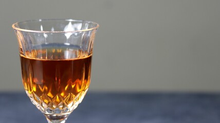 Closeup of a glass of brown cocktail on a gray background