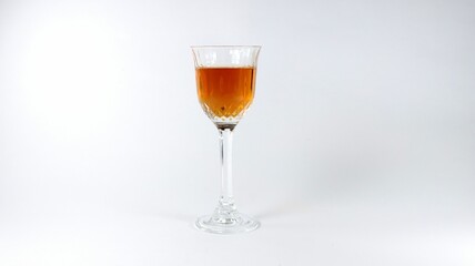 Closeup of a glass of brown cocktail on a white background