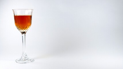Closeup of a glass of brown cocktail on a white background with copy space