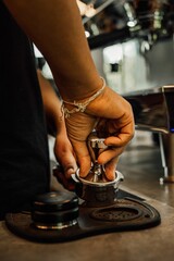 Barista is tamping freshly ground coffee into a portafilter prior to brewing