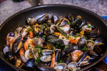 Closeup shot of a culinary dish featuring cooked shrimp and clams in a pan.