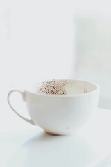 Ceramic mug filled with warm, creamy hot chocolate sits on a wooden table in a cozy atmosphere