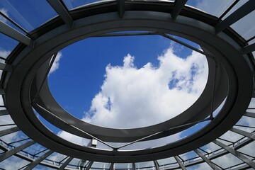 Low angle of a glass ceiling of a modern building under a blue cloudy sky in Berlin - Powered by Adobe