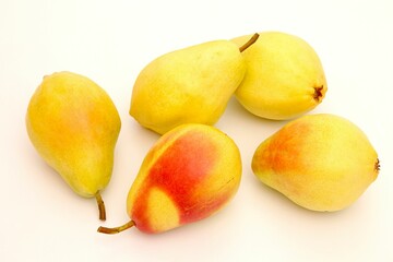 five yellow pears and one orange pear sit on the white surface