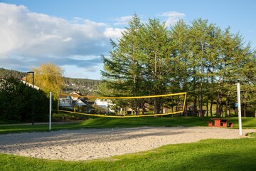 Volleyball court in a lush, green park setting, surrounded by trees and foliage