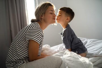 Happy mother and her little son relaxing in bed in morning hours